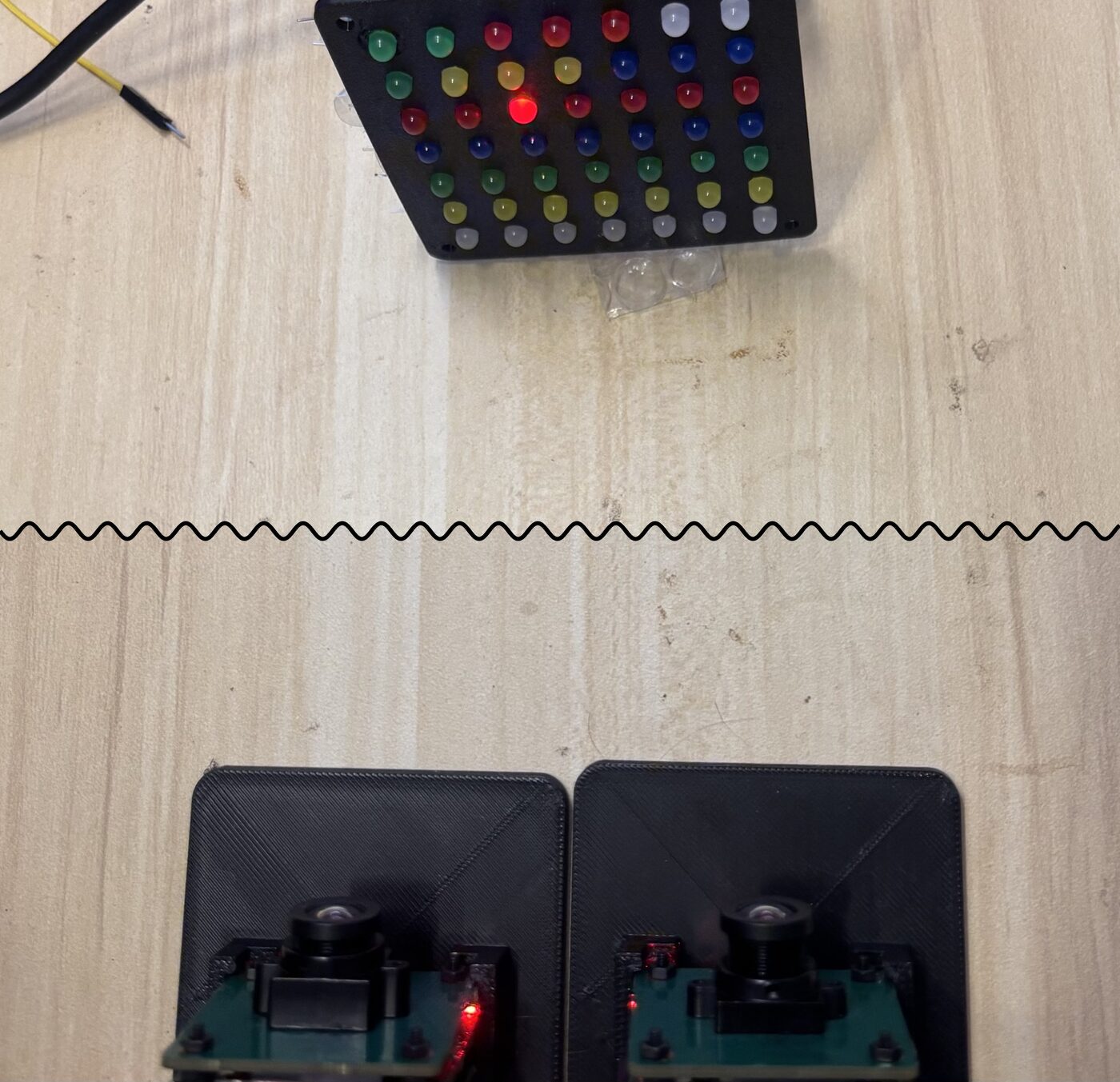 Two cameras in printed stands in front of the LED panel